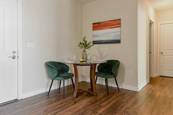 A dining room with a table and two green chairs.